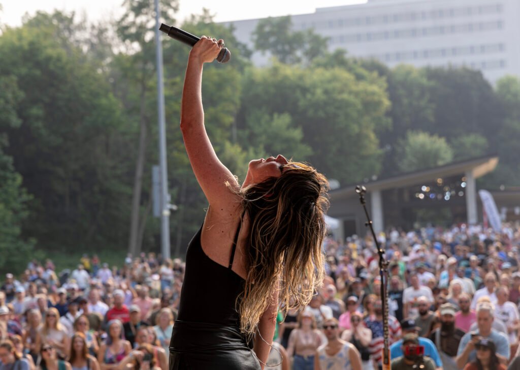 Singer performing at Mile of Music Festival with large crowd